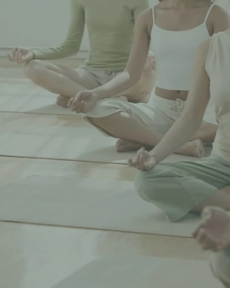 Tres mujeres sentadas en el suelo con las piernas cruzadas practicando meditación.