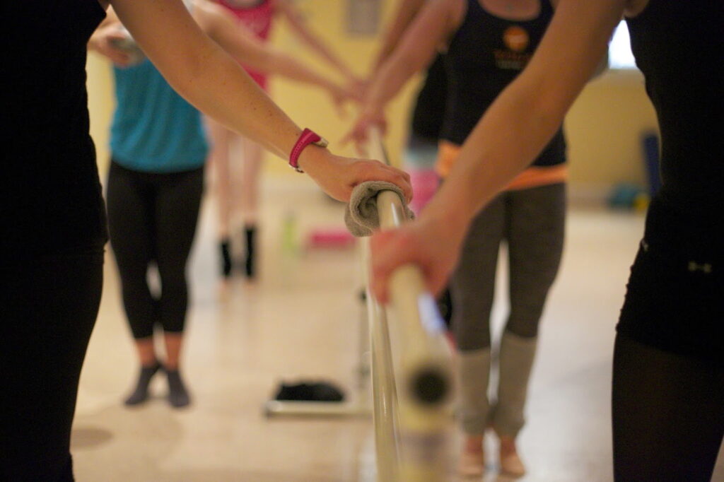Mujeres en torno a una barra practicando balletfit.