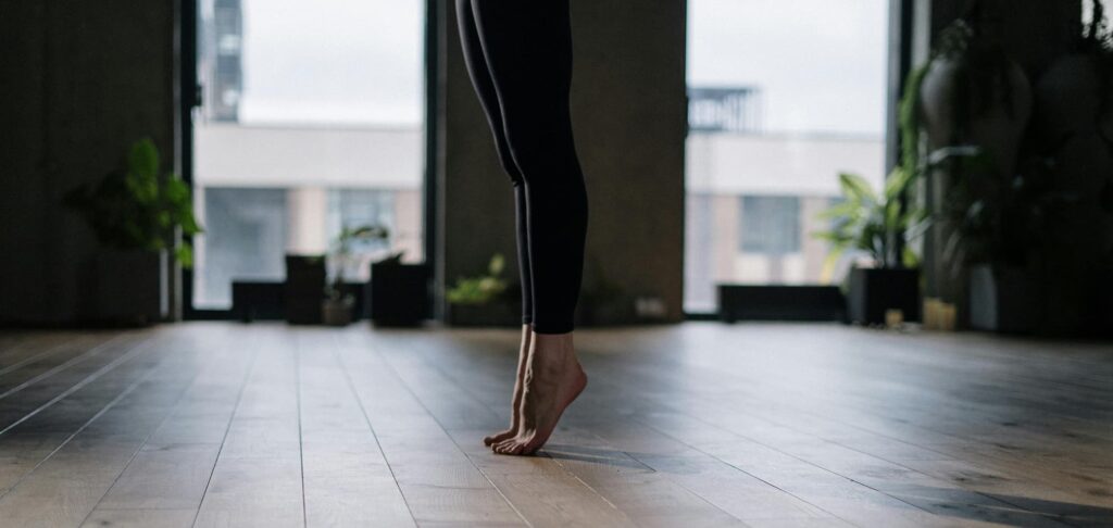 Mujer de pie a contraluz practicando pilates.